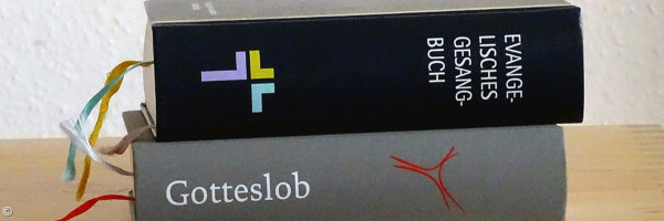 Evangelisches Gesangbuch und Gotteslob liegen aufeinander